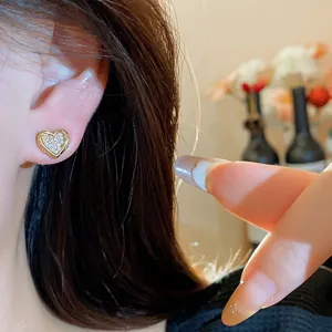 Close-up of heart-shaped 18k gold plated stud earring with sparkling zircon inlay