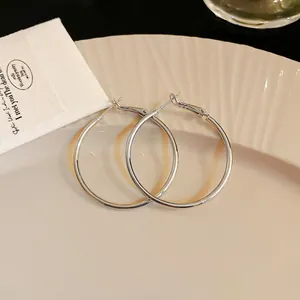 Close-up of minimalist silver round hoop earrings on a textured cream plate