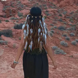 Back view of a woman wearing a bohemian feathered headband with beads in a desert setting