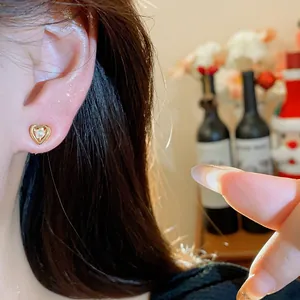 Close-up detail of a delicate heart-shaped pearl stud earring worn on an earlobe