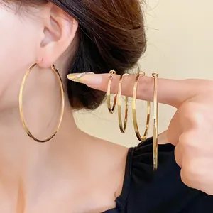 Comparison of various sizes of minimalist gold hoop earrings shown on model's ear and finger