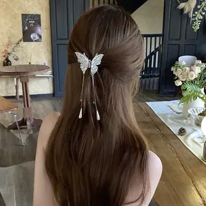 Detailed view of an elegant silver butterfly hair clip with tassels on long brown hair