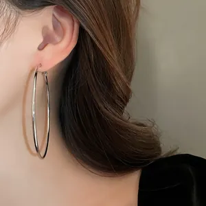Detailed view of a large minimalist polished silver-toned hoop earring worn by a model