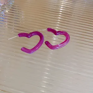 Détail macro de boucles d'oreilles cœur en résine violette avec texture marbrée sur verre