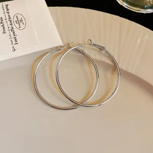 Close-up of minimalist silver hoop earrings with a polished metal finish on a cream plate.