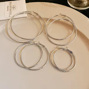Detailed view of four pairs of minimalist silver-tone hoop earrings in varying sizes