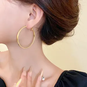 Detailed view of minimalist large gold round hoop earrings worn by a model for a stylish look
