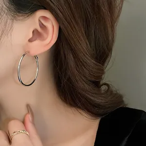 Detail shot of a large silver hoop earring worn by a model for elegant styling.