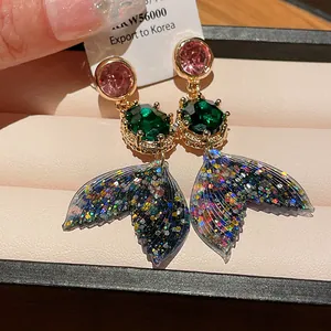 Detailed view of colorful mermaid tail earrings with sparkling rhinestones and glitter