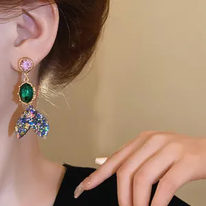 Close-up of a vibrant colorful rhinestone fish tail earring worn by a female model