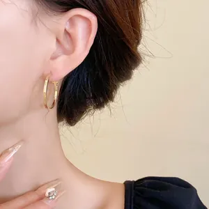 Minimalist polished gold round hoop earrings with surgical steel needle on model