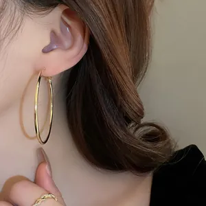 Detailed side view of large gold minimalist hoop earrings worn by a female model.