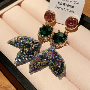 Detailed macro of crystal mermaid tail earrings with colorful glitter in a gift box