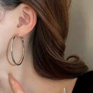 Detailed close-up view of a minimalist large silver metal hoop earring worn by a model