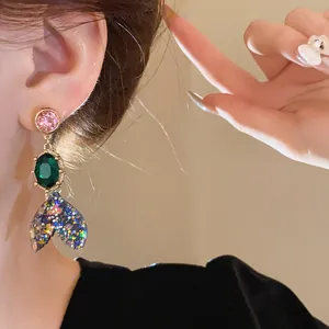 Detailed close-up of a colorful fishtail earring with pink and green crystal accents.