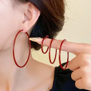 Detailed macro view of minimalist red round hoop earrings in four different sizes