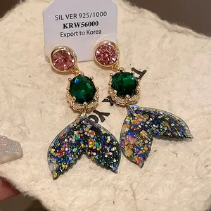 Close-up detail of mermaid tail earrings with sparkling colorful crystals and 925 silver studs