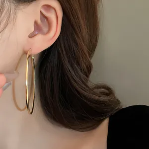 Detailed close-up view of elegant large gold metal round hoop earrings worn on the ear