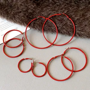 Detailed view of four pairs of minimalist red hoop earrings in various diameters