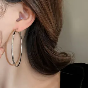 Close-up detail view of a large polished silver metal hoop earring elegantly worn on ear