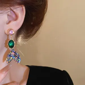 Detailed close-up view of colorful crystal fish tail earring with shimmering glitter on ear