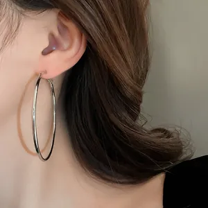 Close-up macro detail of large minimalist silver hoop earrings worn on a female ear
