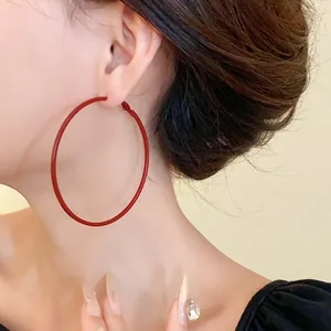 Close-up of a model wearing minimalist large red hoop earrings for a stylish look.