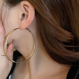 Close-up view of a large minimalist gold hoop earring being worn by a model for a chic look