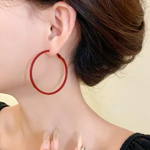 Close-up of minimalist large red hoop earring worn by a model for a stylish look