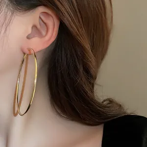 Close-up of minimalist large gold hoop earrings with silver needle shown on model