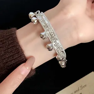 Ethnic style silver bracelet featuring hanging bell charms and a textured metal band