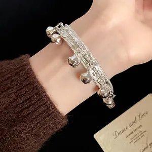 Elegant ethnic style silver textured cuff bracelet featuring dangling mini bells worn on wrist