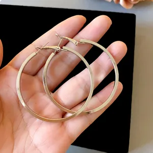 Close-up view of large polished silver hoop earrings held in hand showing size and texture