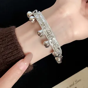 Close-up of silver ethnic cuff bracelet with delicate bell charms and tassel texture