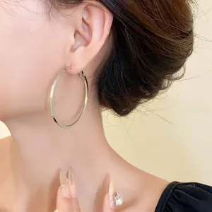 Close-up detail of minimalist oversized stainless steel silver hoop earrings worn on ear