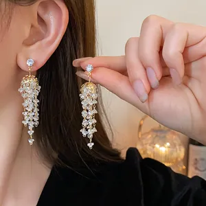 Primo piano di eleganti orecchini a nappa in zirconi placcati in oro finitura lusso