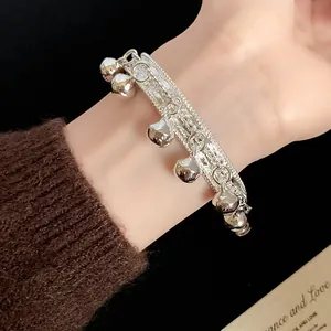Close-up of elegant vintage silver-tone bell charm bracelet with intricate texture on wrist