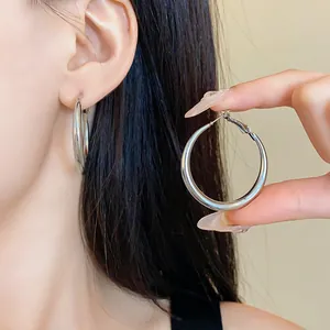Primo piano di grandi orecchini a cerchio geometrici in argento indossati da una modella