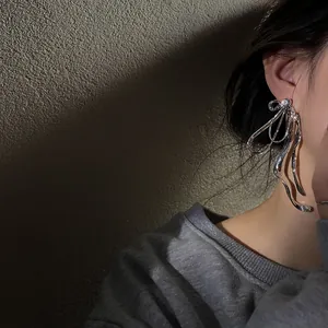 Chic oversized silver metallic bow-knot stud earrings with rhinestone detail on model ear