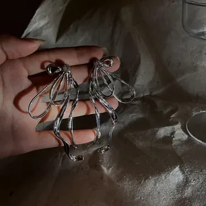 Detailed macro view of oversized silver bow earrings featuring sparkling crystal centers