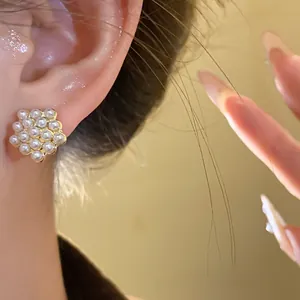 Macro detail of elegant geometric pearl cluster stud earrings with gold-tone settings