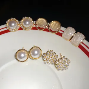 Detail view of a vintage pearl earring set with geometric designs on a white plate