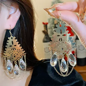 Detailed view of elegant gold hollow earrings featuring sparkling glass teardrop pendants