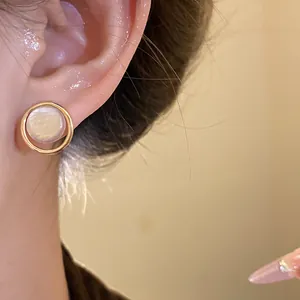 Close-up of elegant French retro pearl stud earring with gold circular frame on model ear