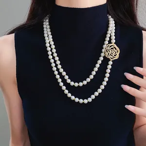 Close-up of double-layer pearl necklace with elegant zircon hollow rose pendant.