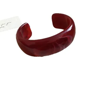Elegante brazalete abierto de acrílico jaspeado burdeos con un diseño minimalista