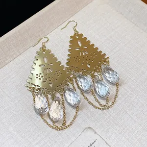 Close-up of elegant gold hollow-out earrings with faceted glass teardrop pendants