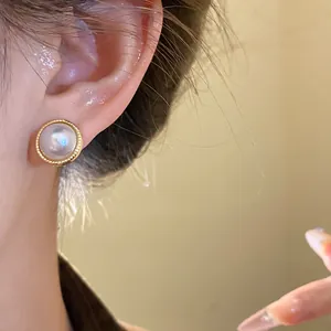Detail shot of a French vintage pearl stud earring with textured gold rim worn on ear