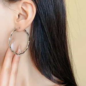 Primo piano che mostra l'effetto elegante di un orecchino a cerchio d'argento a spirale.