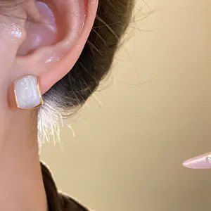 Macro shot of a geometric earring with white pearlescent inlay and gold-tone border